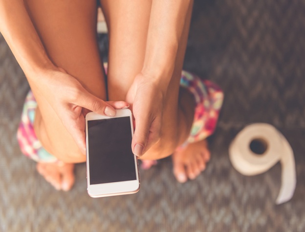 Close up image of someone using their phone while sitting on the toilet